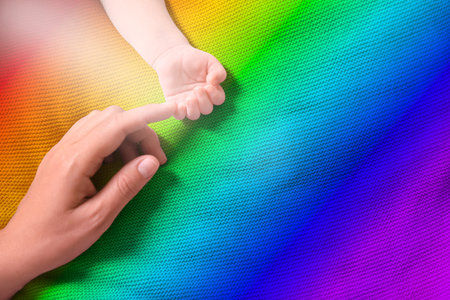 National rainbow baby day. Mother and her little child baby on colorful blanket, top view. Space for...