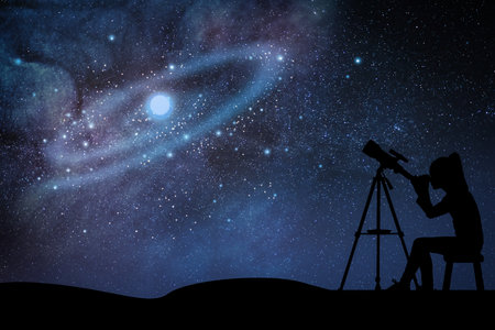 Astronomy. Little girl looking through telescope at starry night outdoorsの写真素材