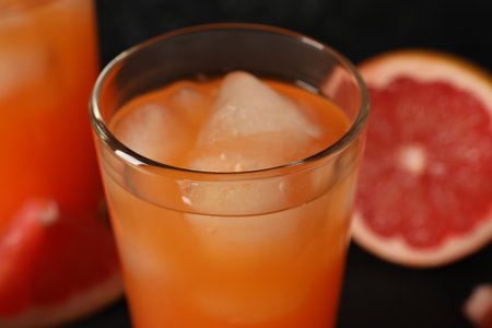 Tasty grapefruit drink with ice in glass on blurred background, closeupの写真素材