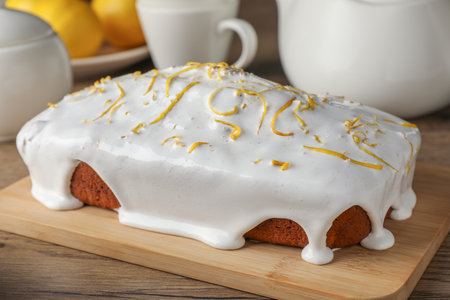 Tasty lemon cake with glaze on wooden table, closeup