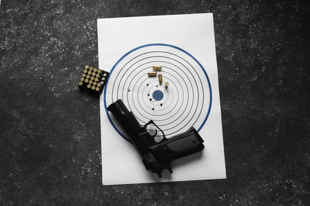 Shooting target, handgun and bullets on dark gray table, top viewの写真素材