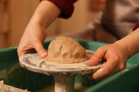 Woman crafting with clay on potter's wheel, closeupの写真素材