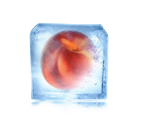 Frozen food. Raw peach in ice cube isolated on whiteの写真素材