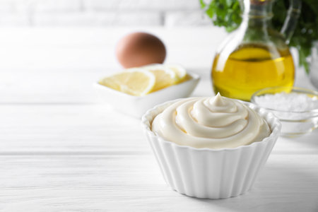 Fresh mayonnaise sauce in bowl on white wooden table, space for textの写真素材