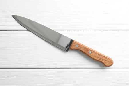 One sharp knife on white wooden table, top view