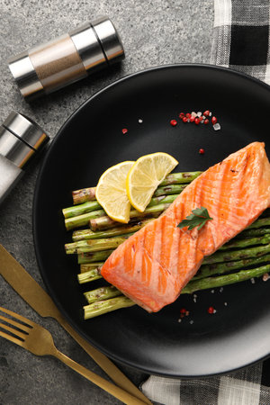 Tasty grilled salmon with asparagus, lemon and spices served on gray table, flat layの写真素材