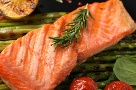 Tasty grilled salmon with tomatoes, asparagus and rosemary on plate, closeupの写真素材