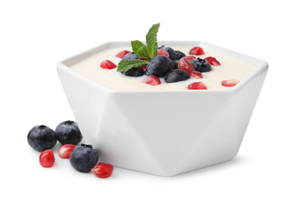 Bowl of delicious semolina pudding with blueberries, pomegranate and mint isolated on whiteの写真素材