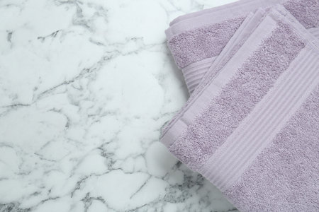 Violet terry towels on white marble table, top view. Space for textの写真素材