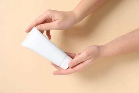 Woman with tube of hand cream on beige background, closeupの写真素材