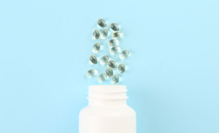 Bottle and vitamin capsules on light blue background, top viewの写真素材