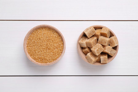 Different types of brown sugar in bowls on white wooden table, flat layの写真素材