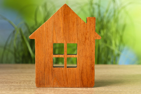 Mortgage concept. House model on wooden table against blurred green backgroundの写真素材