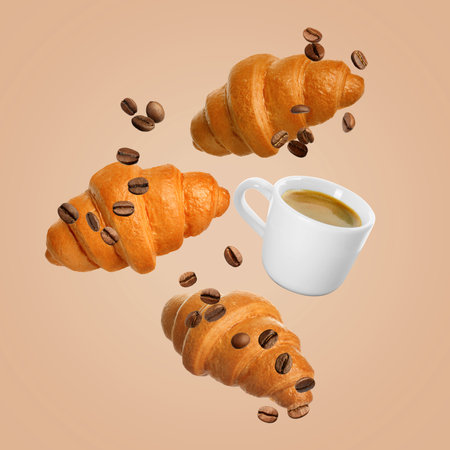 Fresh croissants, aromatic coffee and roasted beans in air on peach color backgroundの写真素材