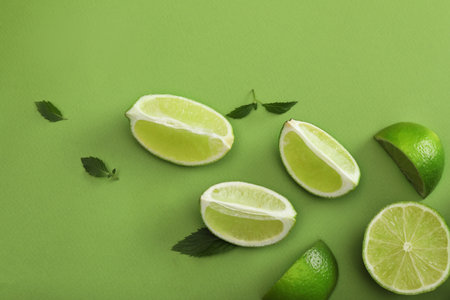 Flat lay composition with fresh limes and leaves on green backgroundの写真素材