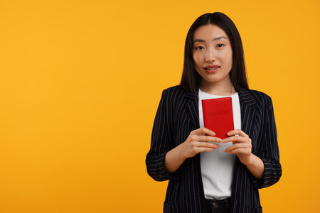 Immigration. Woman with passport on orange background, space for textの写真素材