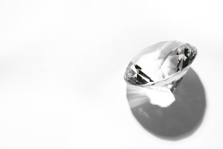One beautiful shiny diamond on white background, above view. Space for textの写真素材
