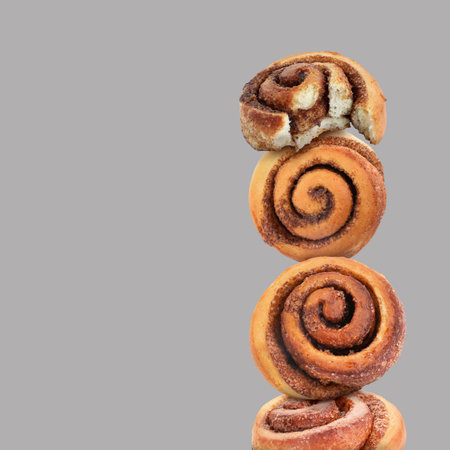 Cinnamon rolls balancing on gray background, space for textの写真素材