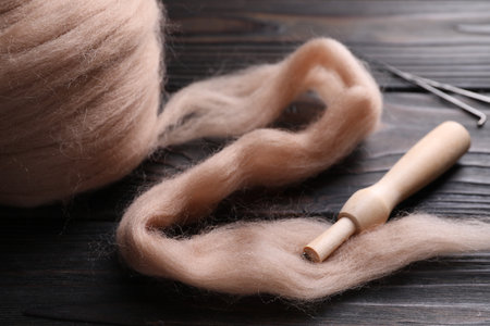 Beige felting wool and needle holder on wooden table, closeup