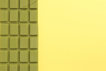 Pieces of tasty matcha chocolate bar on yellow background, top view. Space for textの写真素材