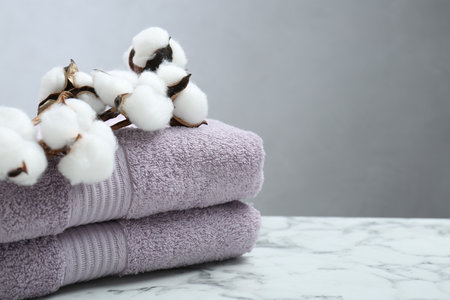 Violet terry towels and cotton flowers on white marble table, closeup. Space for textの写真素材