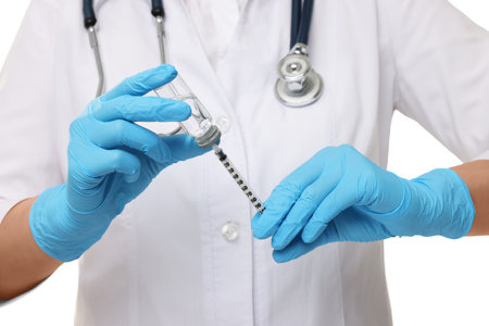 Doctor filling syringe with medication from glass vial on white background, closeupの写真素材