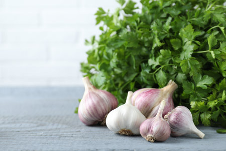 Fresh raw garlic and parsley on gray wooden table, space for textの写真素材