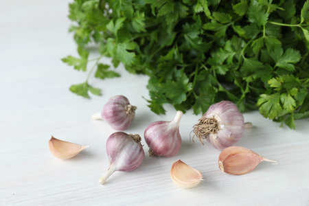 Fresh raw garlic and parsley on white wooden table, closeupの写真素材