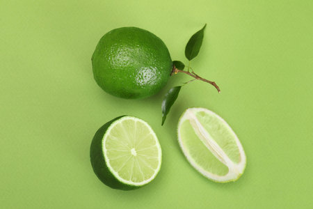 Flat lay composition with fresh limes and leaves on green backgroundの写真素材