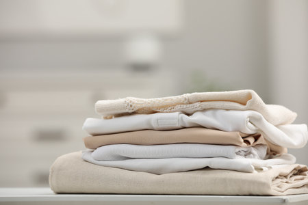 Stack of different folded clothes on white table indoors, closeupの写真素材