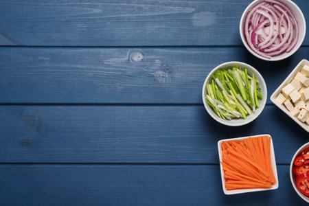Cooking delicious ramen soup. Different fresh ingredients in bowls on blue wooden table, flat lay. Space for textの写真素材