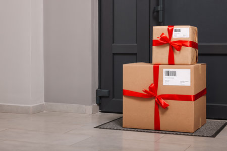 Christmas gift boxes on floor near door, space for text. Sending present by mailの写真素材