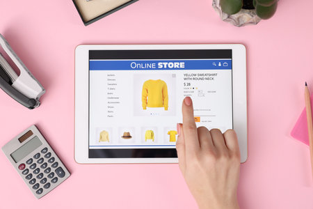 Woman with tablet shopping online on pink background, top viewの写真素材