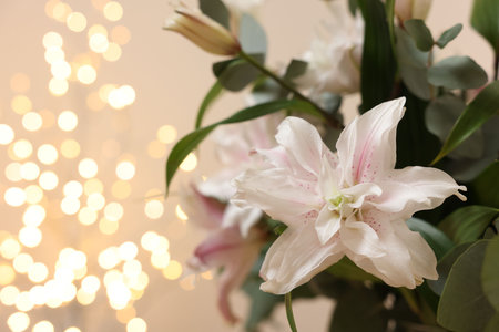 Beautiful lily flower against beige background with blurred lights, closeup. Space for textの写真素材