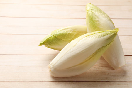 Raw chicories on wooden table, closeup. Space for text