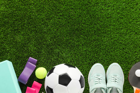 Different sport equipment and sneakers on green grass, flat lay. Space for textの写真素材
