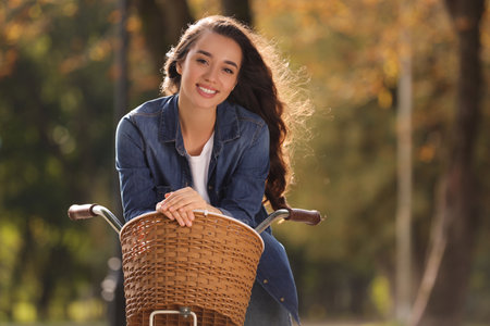 Young woman with bicycle in autumn park, space for textの写真素材