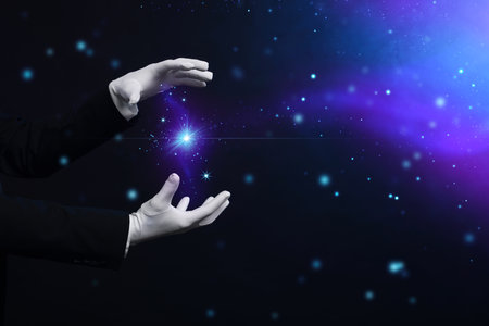 Magician in gloves showing trick on dark background, closeup. Space for textの写真素材