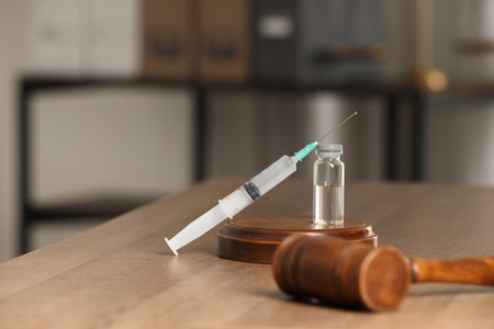 Law concept. Gavel, syringe and glass vial on wooden table, space for textの写真素材