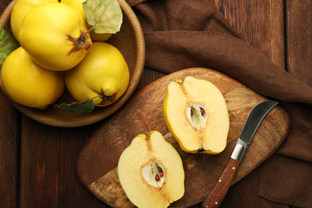 Tasty ripe quince fruits and knife on wooden table, flat layの写真素材