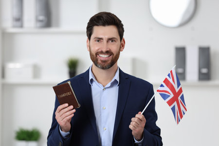 Immigration. Happy man with passport and flag of United Kingdom indoorsの写真素材