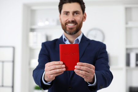 Immigration. Happy man with passport indoors, selective focusの写真素材