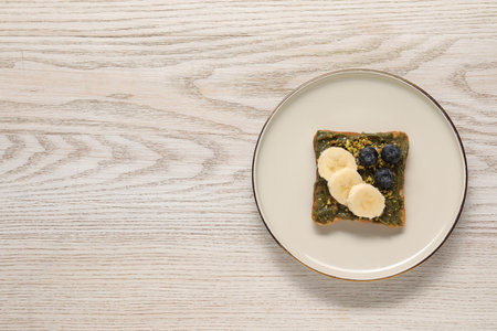 Toast with tasty pistachio butter, banana slices, blueberries and nuts on white wooden table, top view. Space for textの写真素材