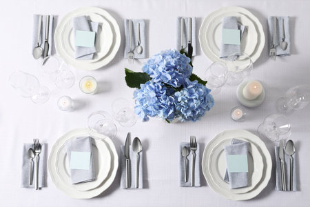 Beautiful table setting with blank cards, candles and floral decor, flat layの写真素材