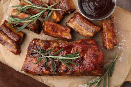 Tasty roasted pork ribs served with sauce and rosemary on table, top viewの写真素材