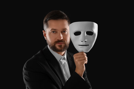 Multiple personality concept. Man with mask on black backgroundの写真素材