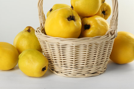 Basket with delicious fresh ripe quinces on white wooden tableの写真素材