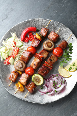 Delicious shish kebabs with vegetables on gray textured table, top viewの写真素材