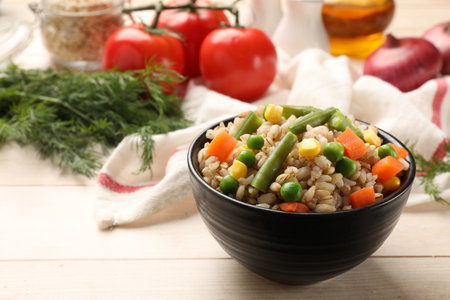 Delicious pearl barley with vegetables in bowl on wooden table, closeup. Space for textの写真素材