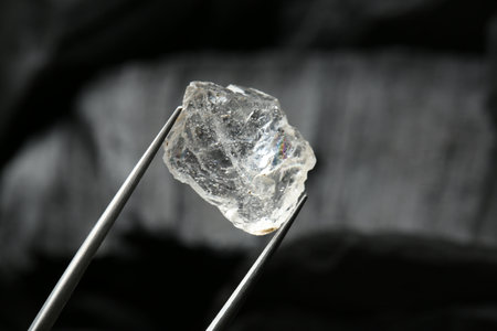 Tweezers with shiny rough diamond on dark background, closeupの写真素材